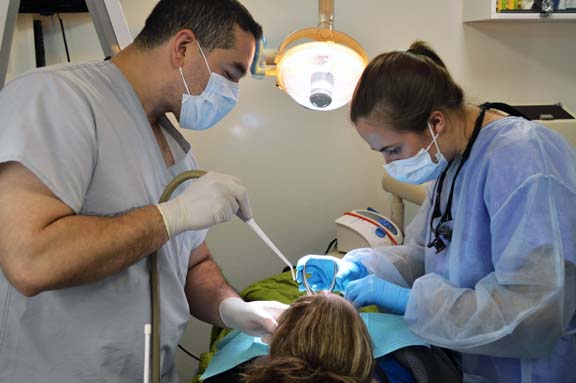 Omar Abarca, dental assistant, and Dr. Rachel Embree, dental resident, examine the site of one woman’s dental pain.