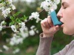 A woman uses an asthma inhaler because of spring allergies.