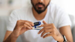 A man using a pulse oximeter at home to learn his blood oxygen level.
