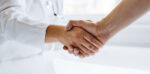 A primary care doctor and patient shake hands to establish relationship.