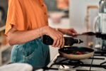 A woman using olive oil as a healthy fat in her cooking.