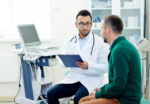 Middle-aged bearded patient having consultation with physician about what tests to run.