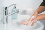 A person properly washing their hands with soap and water to clean away germs.