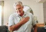 Senior man feeling chest pain near his heart.