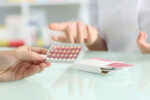 Close up of a woman's hands holding contraceptive pills while talking to gynecologist doctor.