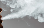 Close-up of a man blowing cigarette smoke from his mouth.