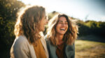 Two young women laughing in the sunlight, boosting serotonin.