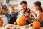 A parent and children carve a pumpkin for Halloween.