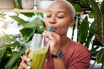 A woman drinking green juice.
