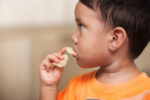 A young kid eating unhealthy food.