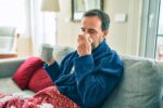 Middle aged man sick with a virus and has body aches.