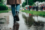 A woman walking in the rain on slippery sidewalk during the spring.