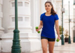 A woman walking while carrying hand weights.