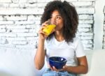 A woman watching her weight drinks fruit juice, oj, orange juice, with her breakfast.