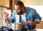 A man experiencing a metallic taste in his mouth from a health condition as he tries tomato sauce.