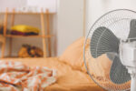 A fan cools a hot summer bedroom for restful sleep.