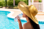 A woman drinking water by the pool trying to get tan due to safe tanning myths.