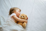 An infant child dreaming while sleeping in bed.