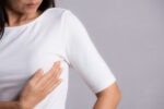 A woman performs a self-breast exam to detect breast abnormalties.