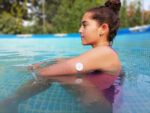 A child at a swimming pool with a diabetes glucose monitor.