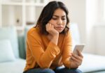 A woman experiencing boredom scrolls through videos on social media.