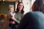 A new mom with her newborn at a lactation support group for breastfeeding.