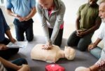 A woman performing CPR uses a CPR-compatible song to deliver compressions.