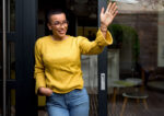 A woman waving hello to a stranger to strengthen social connections and therefore her health due to social interactions.