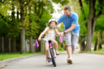 A child learning how to ride a bike with the help of their parent.