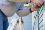 A man at risk of orthopedic injuries while putting up holiday lights.