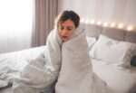 A woman waking up freezing cold in her bed due to natural body temperature regulation processes.