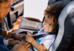 An infant being put in a car seat.