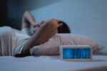 A woman has insomia at night while lying in bed.