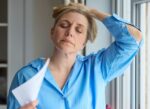 A middle aged woman having a hot flash, symptom of menopause that can be treated with hormone replacement therapy (HRT).