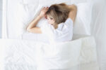 A woman sleeping on her stomach which can lead to pillow prints and wrinkles.