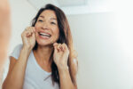 A woman flossing to reduce her risk of stroke.