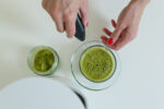 A woman mixing powdered greens in water to boost her health.