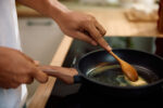 A woman using butter as her cooking fat in a pan while cooking.