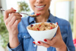 A woman eats healthy cereal for breakfast.