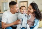 Infant has favorite parent. Parents pose with infant.
