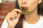 A woman eats seaweed as a part of the Okinawa diet.