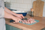 A woman cooking chicken as a healthy protein source.
