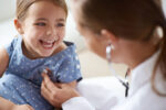 A cardiologist listens to a child with a heart condition's heart.