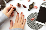 A woman painting her nails with nail polish.