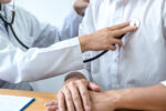 A doctor listening to a man's heart who has cardiovascular disease.